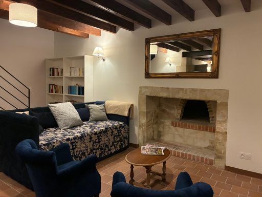 Intérieur d'un salon avec canapé, fauteuils, table basse et cheminée en pierre.