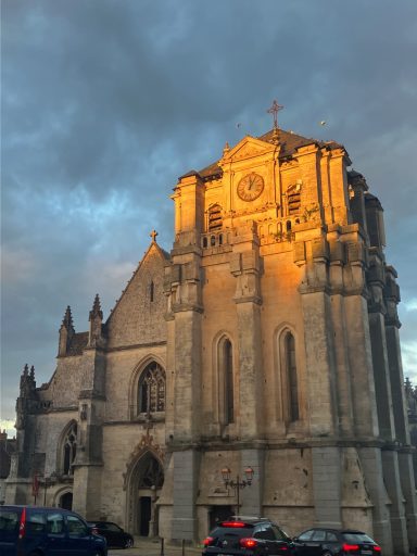 Église en pierre avec une lumière dorée, ciel nuageux en arrière-plan.