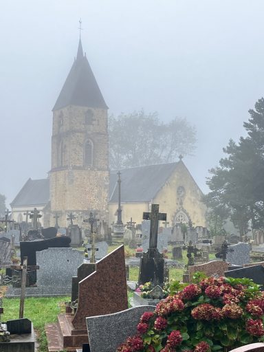 Église en pierre entourée de tombstones, par une matinée brumeuse.